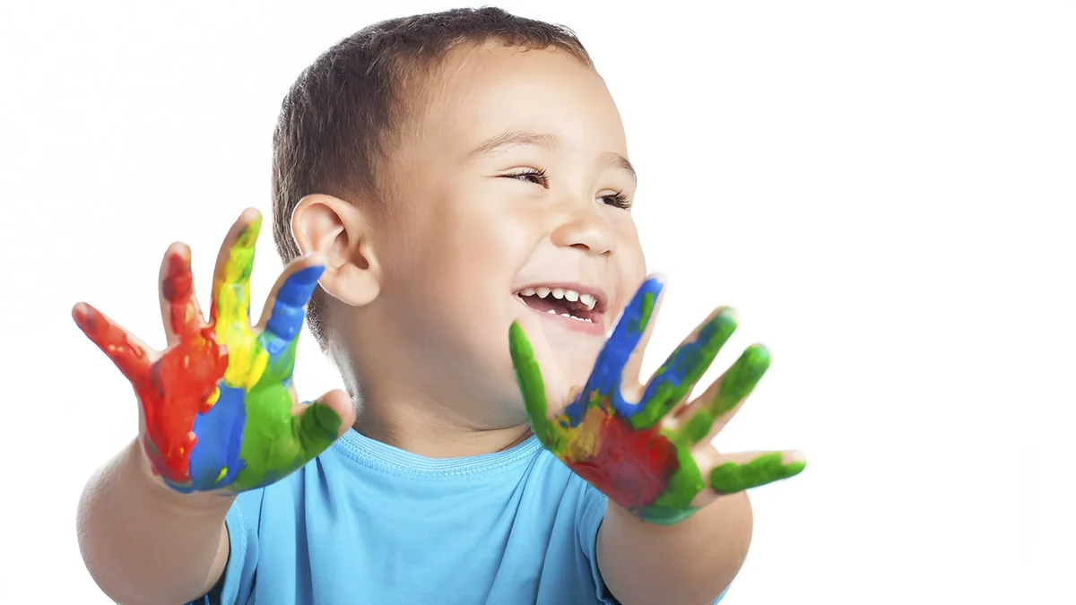 Criança sorrindo com as mãos sujas de tinta